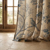 Hem of a blue bird toile curtain resting on a stone floor