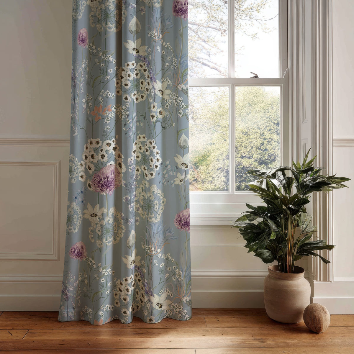 Blue floral curtain panel with dandelion wildflower print hanging by a white window