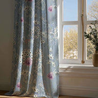 Full-length blue floral curtain resting on a wooden floor