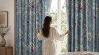Woman opening blue floral curtains in a bedroom