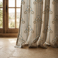 Hem of a blue and gold ornamental stripe curtain resting on a stone floor