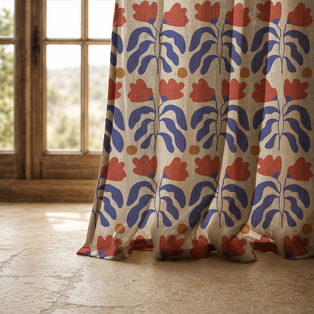 Hem of a blue and red cut out leaf curtain resting on a stone floor