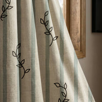 Blue stripe leaf sprig curtain panel beside a rustic wooden window