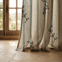 Hem of a blue stripe leaf sprig curtain resting on a stone floor