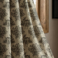 Charcoal rabbit toile curtain panel beside a rustic wooden window