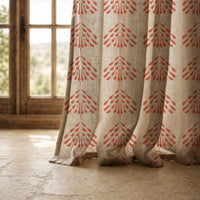 Hem of a coral palmette block print curtain resting on a stone floor