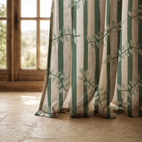 Hem of a green stripe leaf vine curtain resting on a stone floor