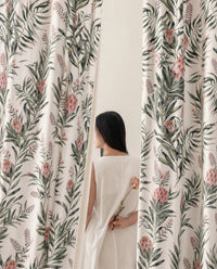 Woman standing between two green willow chinoiserie floral curtain panels