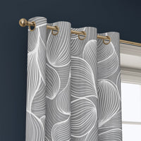 Grommet top of a grey line art leaf curtain on a brass rod