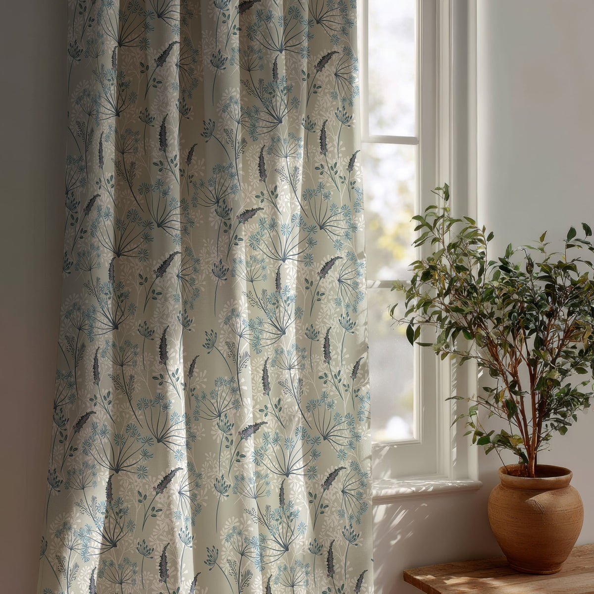 Light blue meadow flower curtain beside a potted olive tree