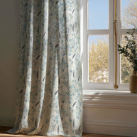 Full-length light blue meadow flower curtain draping to a wooden floor