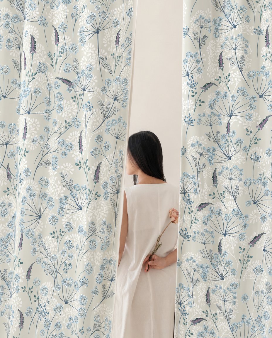 Woman standing between two light blue meadow flower curtain panels