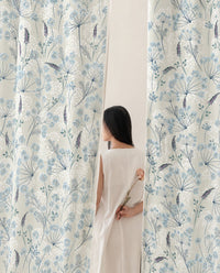 Woman standing between two light blue meadow flower curtain panels