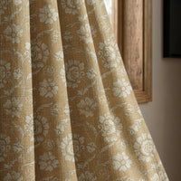 Mustard floral damask curtain panel beside a rustic wooden window