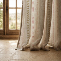 Hem of a natural folk ticking stripe curtain resting on a stone floor