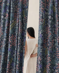 Woman standing between two navy wildflower meadow curtain panels
