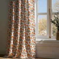Full-length orange block print floral curtain draping to a wooden floor
