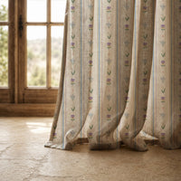 Hem of a pastel ditsy floral stripe curtain resting on a stone floor