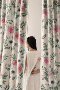 Woman standing between two pink rose floral curtain panels