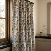 Purple block print floral curtain on a black rod by a window