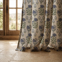 Hem of a purple block print floral curtain resting on a stone floor