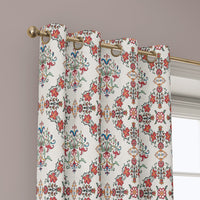 Grommet top of a red medallion tile curtain on a brass rod