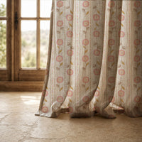 Hem of a rose pink floral stripe curtain resting on a stone floor