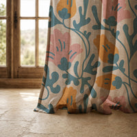 Hem of a teal and pink abstract floral curtain resting on a stone floor