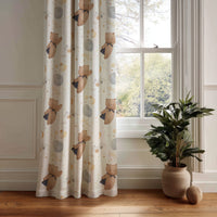 Teddy bear and moon nursery curtain panel hanging by a white window