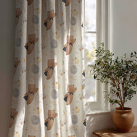 Teddy bear and moon nursery curtain beside a potted olive tree