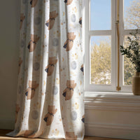 Full-length teddy bear and moon nursery curtain draping to a wooden floor