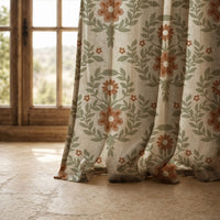 Hem of a terracotta folk floral curtain resting on a stone floor
